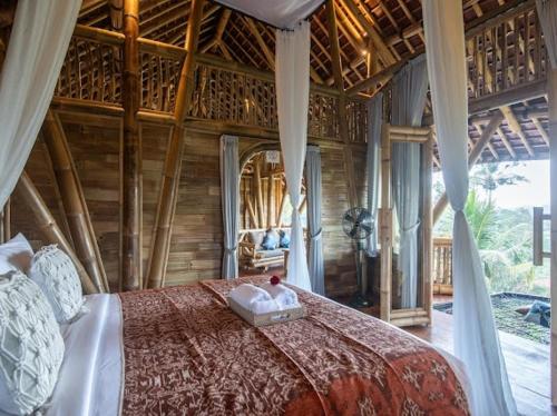 a bedroom with a large bed in a room at Uma Bali-Bamboo House in Selat