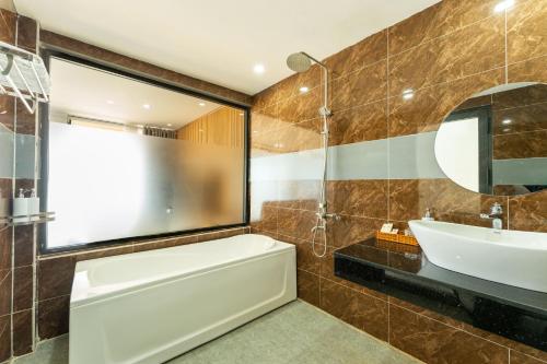 a bathroom with a tub and a sink and a mirror at Orange Resort in Phú Quốc