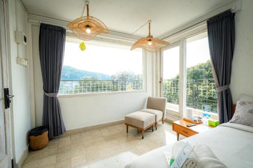 a bedroom with a bed and a chair and a window at Wisma Nirwana Tretes near Cimory Prigen in Prigen