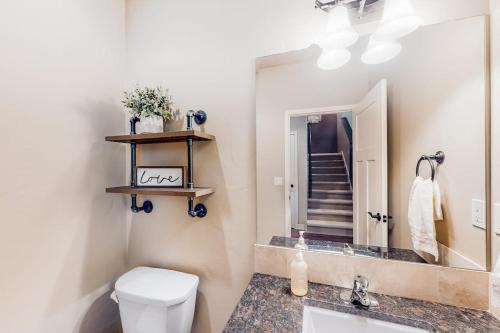 a bathroom with a toilet and a sink and a mirror at Cedar Point Hideaway in Columbia Falls