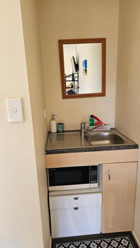 a kitchen counter with a sink and a mirror at Bahara Accommodation in Springfield