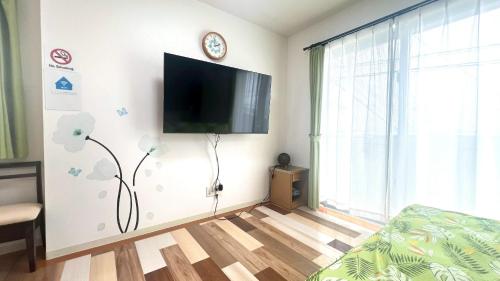 a living room with a flat screen tv on the wall at Guesthouse Yu in Yomitan