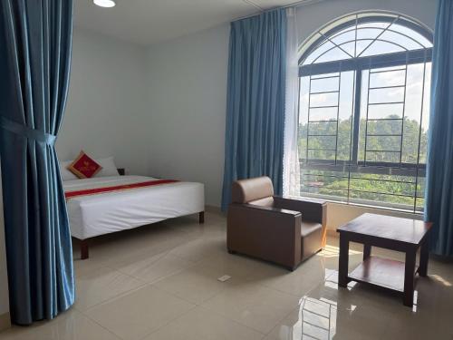 a bedroom with a bed and a chair and a window at Hotel T88 in Ấp Trảng