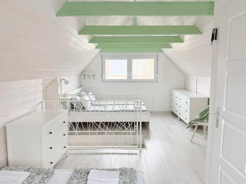 a bedroom with white walls and a ceiling with green beams at Helló Zsóry Apartman in Mezőkövesd
