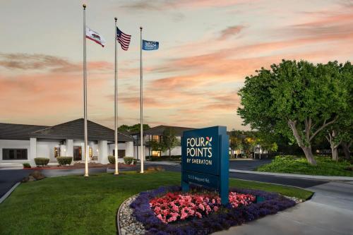 a sign in a flower bed in front of a hotel at Four Points by Sheraton Pleasanton in Pleasanton