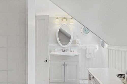 a white bathroom with a sink and a mirror at The Wolfeboro House in Wolfeboro