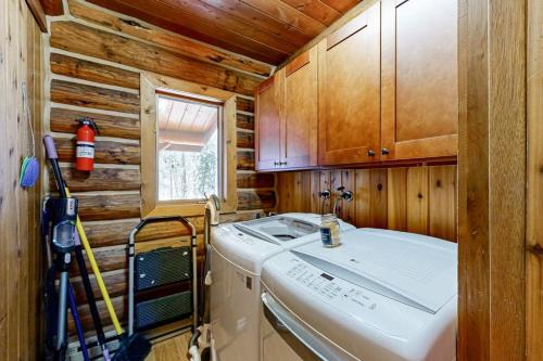 a small kitchen with a washing machine and wooden walls at Blacktail Cabin in Somers