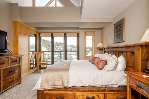 a bedroom with a large bed and a tv and windows at Shoshone 1986 in Big Sky