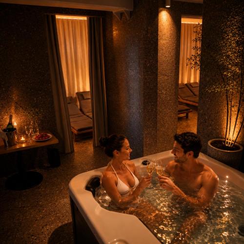 a man and woman sitting in a bath tub with wine glasses at Natura Amon in Podčetrtek