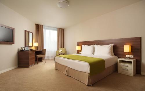 a hotel room with a large bed and a desk at Parklane Resort and SPA in Saint Petersburg