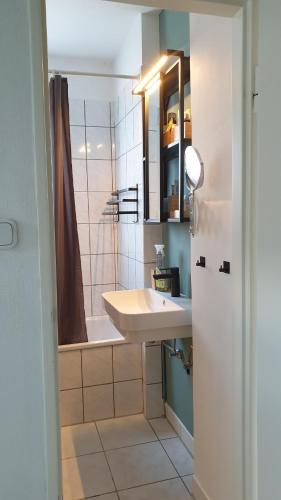 a bathroom with a sink and a tub and a mirror at Ferienwohnung Bad Vilbel in Bad Vilbel