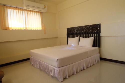 1 dormitorio con cama blanca y cabecero negro en J-Safe Guesthouse, en Sukhothai