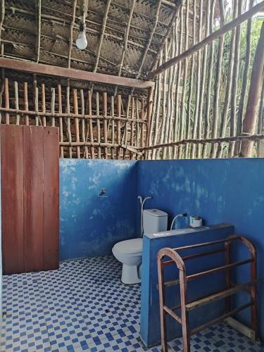 a bathroom with a toilet and a blue wall at The Alpha Monkey hotel & Tree house in Tangalle