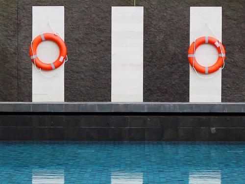 a swimming pool with orange life rings on a wall at HARRIS Hotel Sentul City Bogor in Bogor