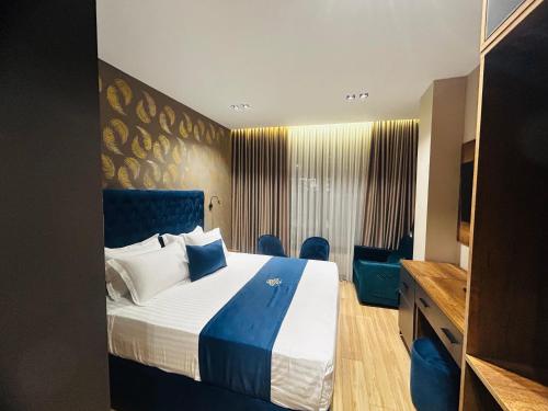 a hotel room with a large bed and blue chairs at Hotel Shopi Residence in Elbasan