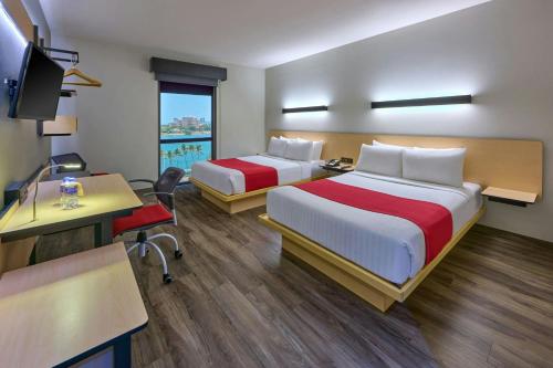 a hotel room with two beds and a desk at City Express Plus by Marriott Puerto Vallarta in Puerto Vallarta
