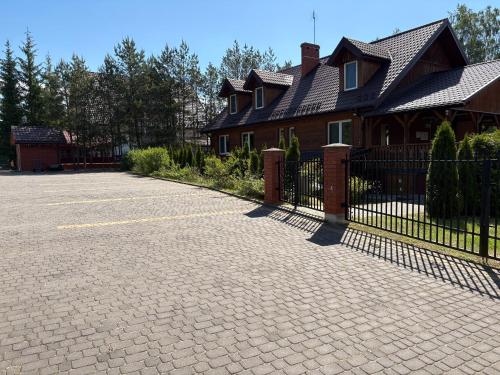 a brick driveway in front of a house with a fence at "Rowerowa Przystań" turystyka wiejska & agroturystyka nad jeziorem Serwy w sercu Puszczy in Sucha Rzeczka