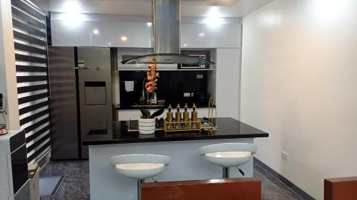 a kitchen with a counter with two stools at Cai Residence - Stylish 2BR Staycation near EK & Tagaytay Gateway in Santa Rosa