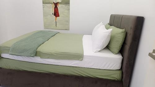 a bed with green and white sheets and pillows at Cai Residence - Stylish 2BR Staycation near EK & Tagaytay Gateway in Santa Rosa