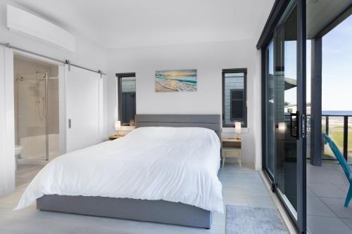 a bedroom with a large white bed and glass walls at Saratoga Beach Villa 4 in Oyster Bay