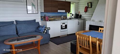 a living room with a blue couch and a kitchen at Suvikoti in Lokalahti