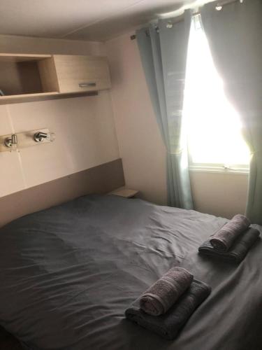 a bed with two pillows on it with a window at Omaha beach mobilhome in Colleville-sur-Mer