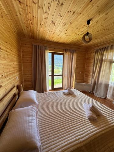a large bed in a wooden room with a window at Ivlita in Mestia