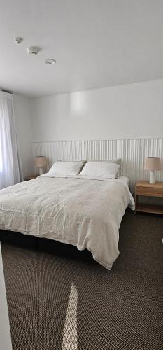 a bedroom with a large bed and two tables at Waves Kaikoura Waterfront Apartment #1 in Kaikoura
