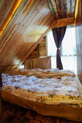 a bed in a room with a wooden ceiling at Sameer Mountain View Cottage in Tanah Rata
