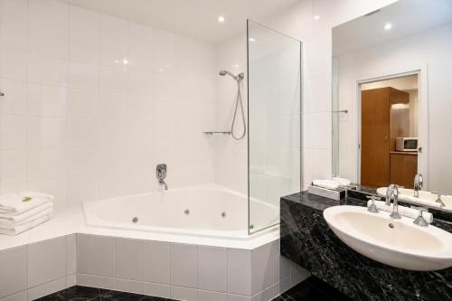 a white bathroom with a tub and a sink at Belmercer Motel in Geelong