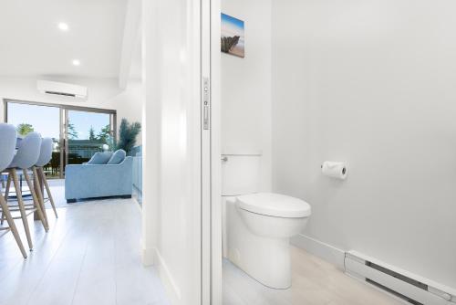 a white bathroom with a toilet and blue chairs at Saratoga Beach Villa 4 in Oyster Bay