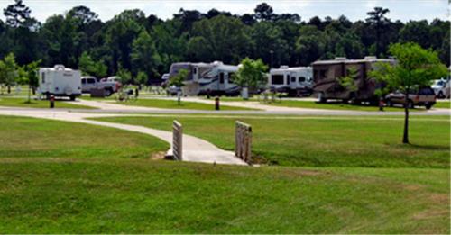 a park with two rvs parked in the grass at Red Shoes RV Park and Chalets in Kinder