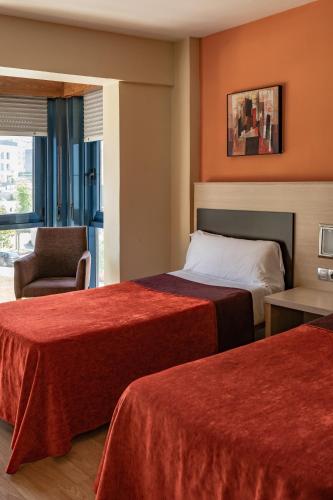 a hotel room with two beds and a chair at Hotel SPA GBC Avenida Pontevedra in Pontevedra