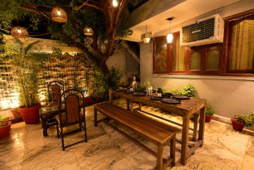 a table and a bench in a room with plants at Peach stay in Mount Ābu