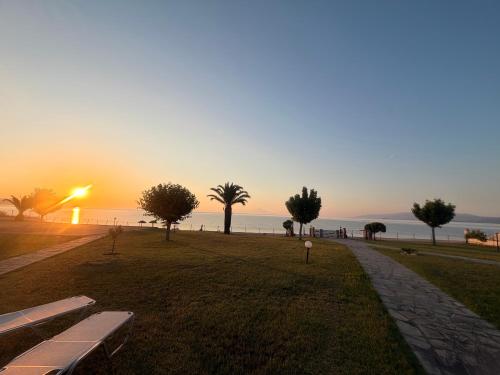 a park with benches and trees and the ocean at sunset at Villa Nikoleta - Beach Front luxury villa with beach access in Akti Salonikiou