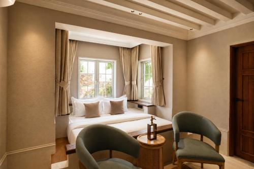 a bedroom with a bed and two chairs and a window at YAMA Villa Udaipur in Udaipur