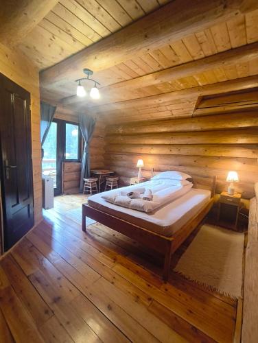 a bedroom with a bed in a wooden cabin at Pensiunea Larix in Răchiţele