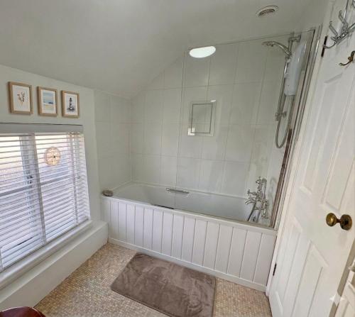 a white bathroom with a tub and a window at Coach House Hideaway in Warminster