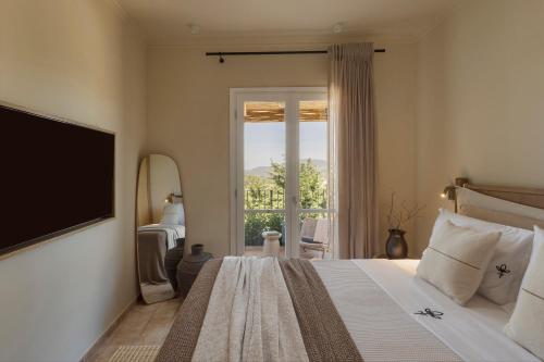 a bedroom with a bed with a television and a window at Anthos Villa in Kardhakáta