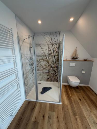 a bathroom with a glass shower with a toilet at MeerZeit 20 in Carolinensiel