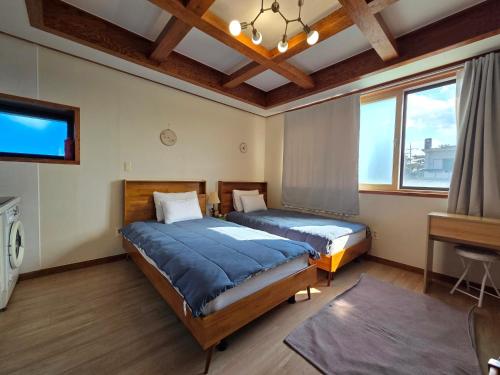a bedroom with two beds and a tv and windows at There Bengdi in Jeju