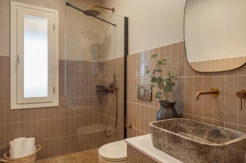 a bathroom with a sink and a toilet and a mirror at Anthos Villa in Kardhakáta