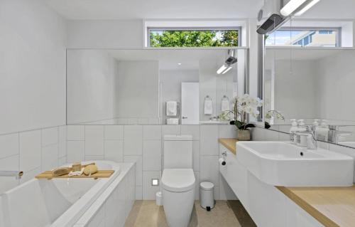 a white bathroom with a toilet and a sink at Stillpoint Retreat in Motungarara