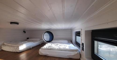 two beds in a room with a round window at Tiny House Scarlet in Dziemiany