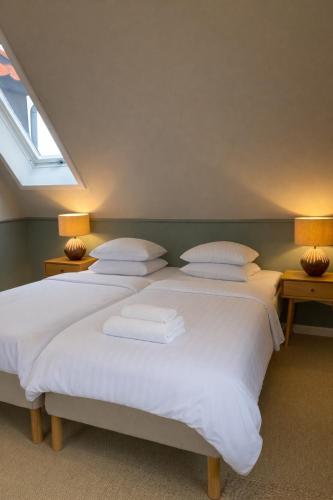 a bedroom with two beds with white sheets and two lamps at Klippen Hotel - Skt Jørgens Gaard in Gudhjem