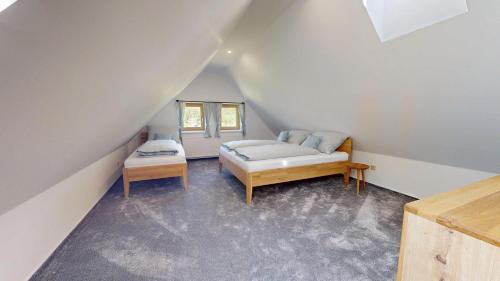 a attic room with a bed and a couch at Apartmány Nová Oleška in Huntířov