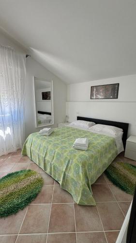 a bedroom with a large bed with a green blanket at Sotto i Lucernai in Cagli