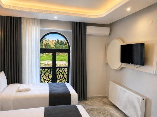 a hotel room with two beds and a window at Kasr-ı Cihan Boutique Hotel in Midyat