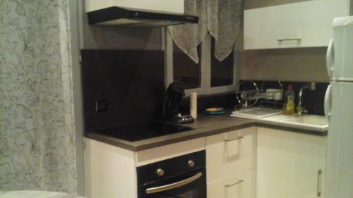 a small kitchen with white cabinets and black appliances at Loft Les Tourelles in Andon