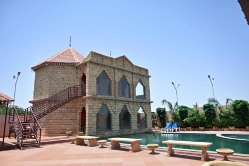 a building next to a swimming pool with a bench at The Royal Valley Resort in Chotila